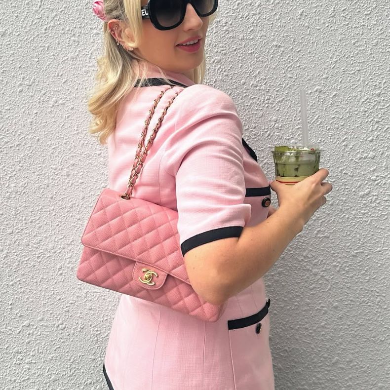 A woman in a pink short sleeve top holding s pink Chanel double flap bag